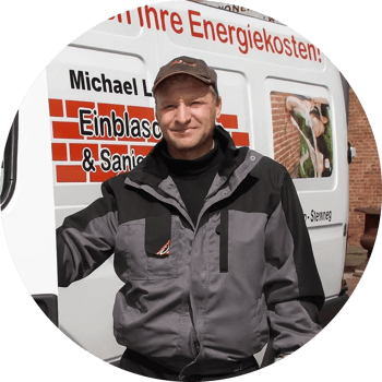 Ein lächelnder Mann mittleren Alters mit Brille und kurzen grauen Haaren.