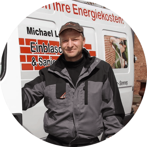 Ein lächelnder Mann mittleren Alters mit Brille und kurzen grauen Haaren.